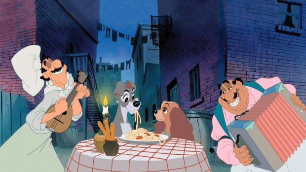 A romantic scene from Lady And The Tramp featuring the two dogs sharing spaghetti at a table in an alley