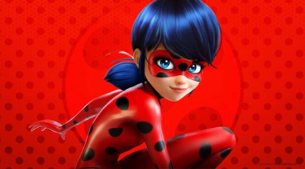 A vibrant ladybug superhero character with blue hair and a red spotted suit posed against a red background