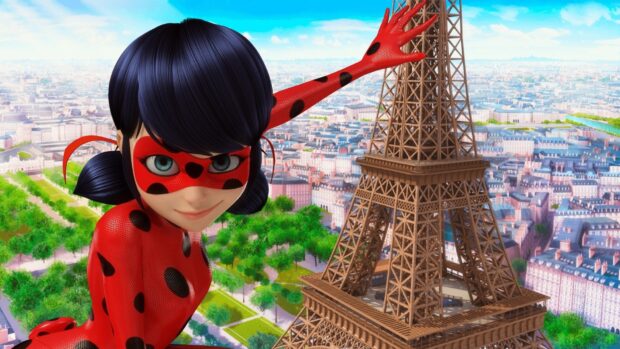 Ladybug character in red and black costume posing near the Eiffel Tower in Paris with a city view in the background