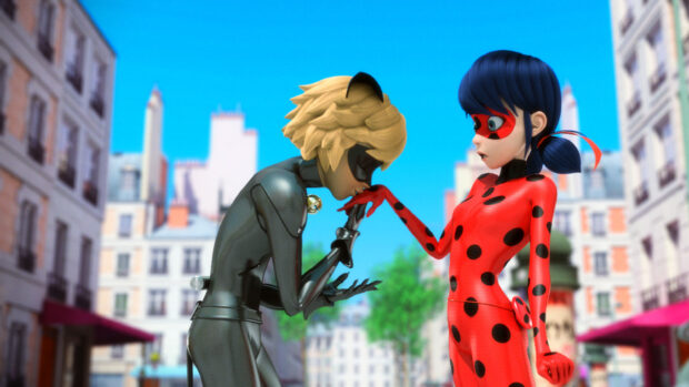 A girl wearing a ladybug suit standing with a boy in a black cat costume in the city street