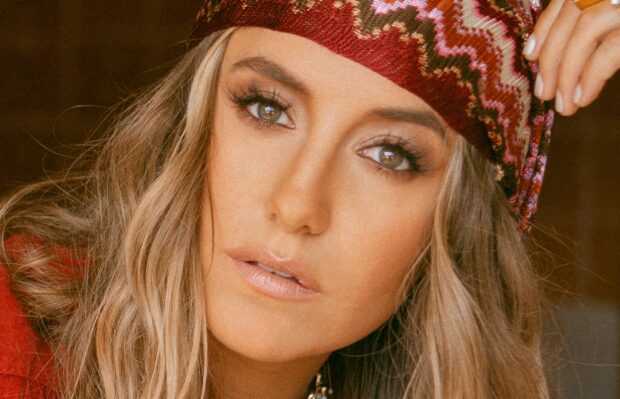 Close up of Lainey Wilson wearing a patterned headscarf and natural makeup