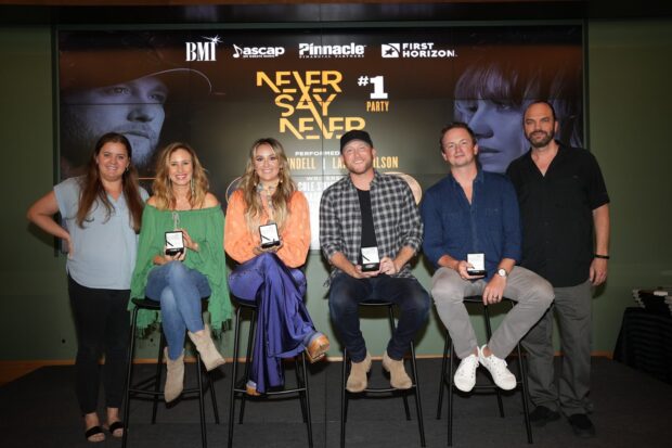 Lainey Wilson and a group of people sitting on stools at an award event