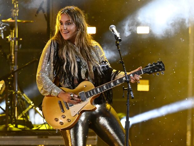 Lainey Wilson playing guitar on stage during a live concert performance