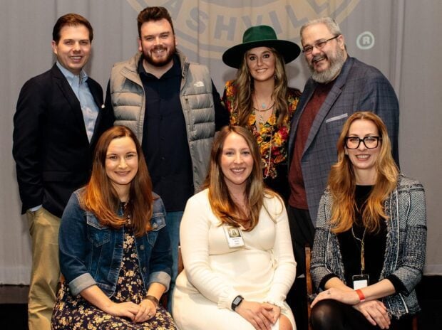 A group of people including Lainey Wilson smiling in a casual indoor setting