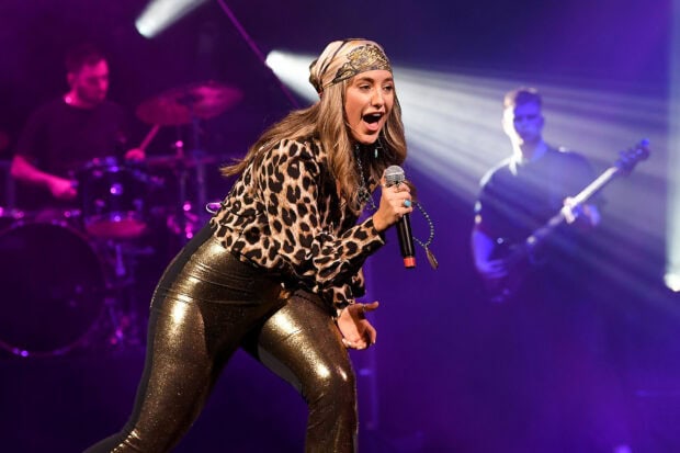 Lainey Wilson singing on stage with band members during a live concert performance
