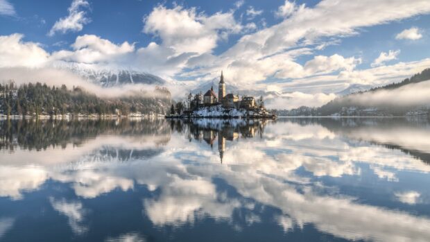 A scenic view of Lake Bled with snow covered island reflecting in the calm water