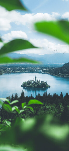 Lake Bled Wallpapers 2K Mobile   A serene view of Lake Bled island surrounded by lush greenery and distant mountains