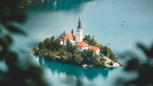 Aerial view of Lake Bled island with historic church and lush greenery surrounded by turquoise water in Slovenia