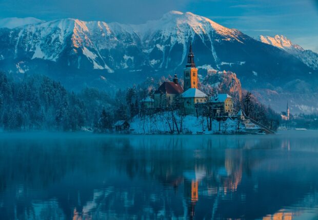 Snowy mountain landscape with Lake Bled and island church at sunrise