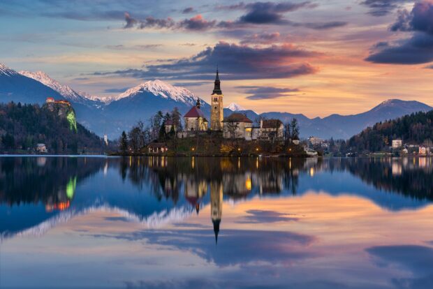 Beautiful Lake Bled scenery with church island and snowy mountains at sunset