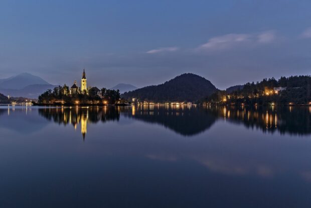 Evening view of Lake Bled with mountains and illuminated island reflections