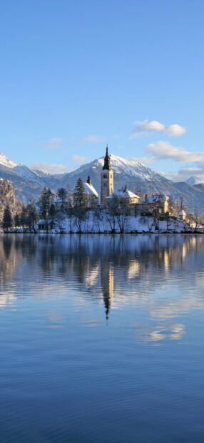 Snow covered island with church reflected on Lake Bled in winter