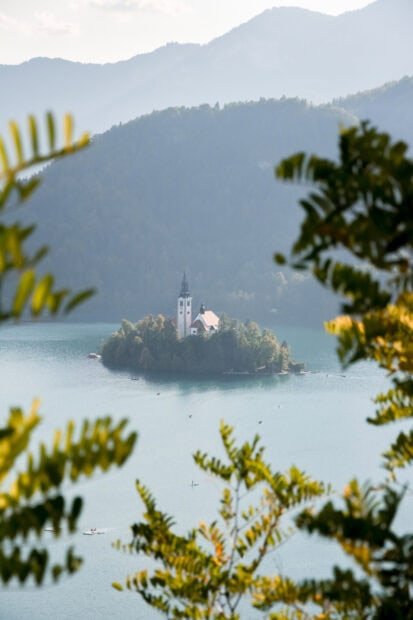 A scenic view of Lake Bled island with a church surrounded by mountains and trees