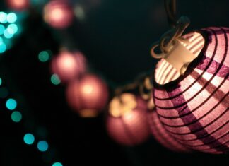 A close up of purple lanterns glowing softly in the dark night with blurred lights in the background
