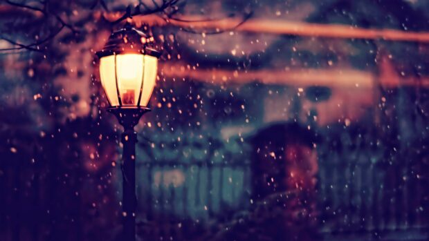 A lantern shines brightly on a rainy evening surrounded by softly falling droplets