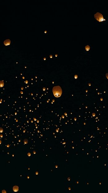 Numerous lanterns floating into the night sky creating a beautiful glowing scene