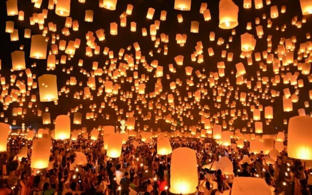 A large crowd releasing lanterns into the night sky during a lantern festival event