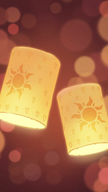 Two glowing lanterns with sun designs floating in a warm night sky