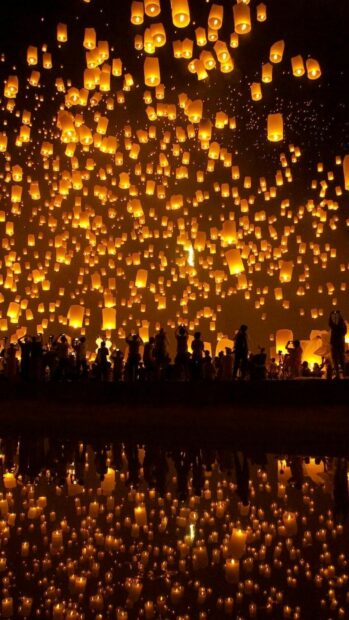 A crowd releasing lanterns floating in the night sky during lanterns festival