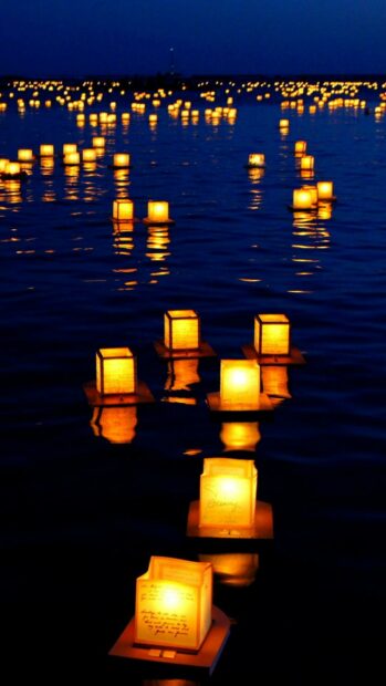 Floating lanterns on water create a peaceful night scene with glowing lanterns
