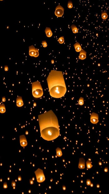 Glowing lanterns float up into the night sky creating a bright lanterns display