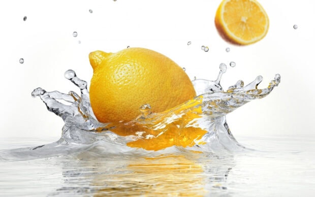 Fresh lemon fruit splash in clear water with juicy lemon slice in background