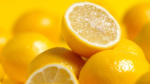 Fresh lemon with detailed texture and juicy segments on a pile of whole lemons