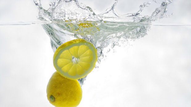 Two lemon fruits splash into clear water with bubbles and splashes