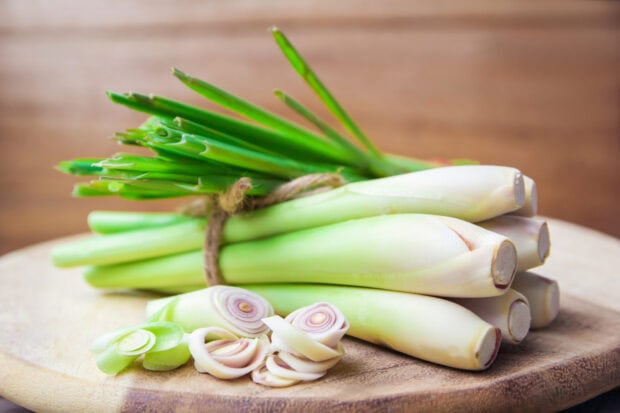 Fresh lemongrass stalks tied with twine and sliced on a wooden cutting board
