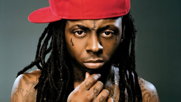 Lil Wayne with tattoos and a red cap looking intensely at the camera