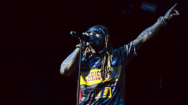 Lil Wayne performing on stage with tattoos and sunglasses