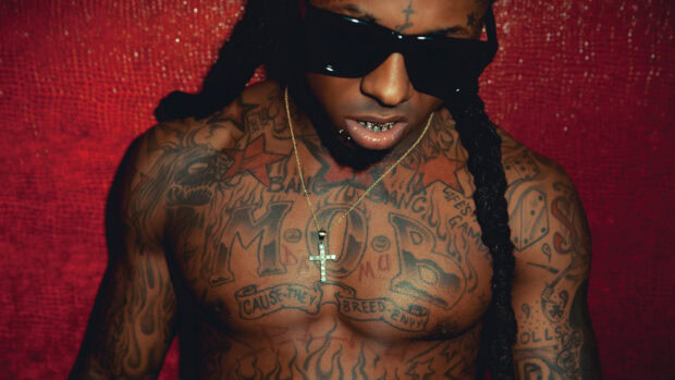 Lil Wayne shirtless with tattoos and a cross necklace wearing sunglasses