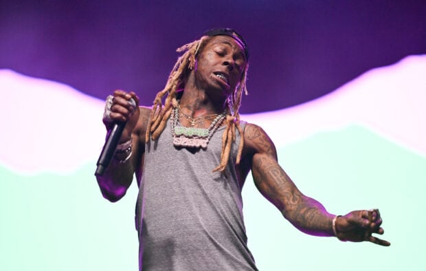 Lil Wayne wearing a gray tank top and chains while performing on stage