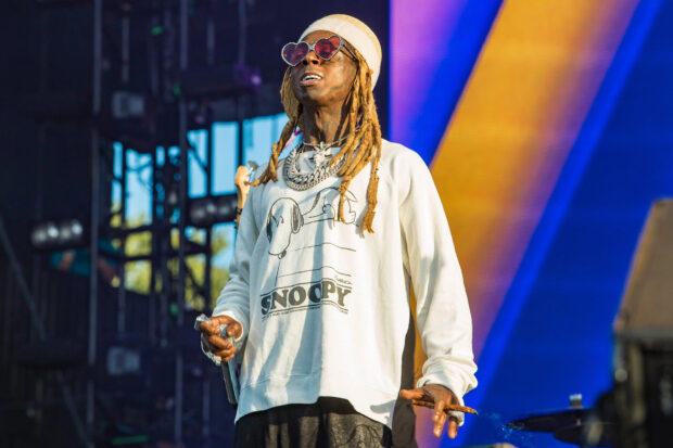 Lil Wayne wearing heart shaped sunglasses and a Snoopy sweatshirt performing on stage