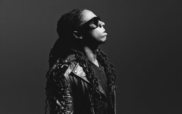 Lil Wayne wearing sunglasses and a studded leather jacket looking upward in black and white portrait