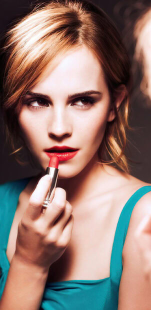 Woman applying red lipstick with a focused expression and flawless skin