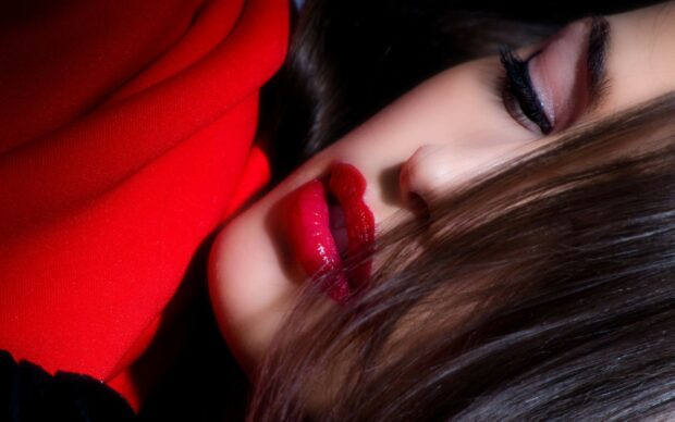 Close up of lips with red lipstick on a woman wearing a red outfit