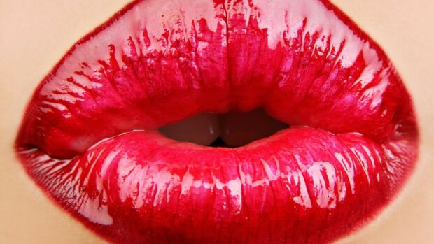 Glossy red lipstick close up showing vibrant texture on lips