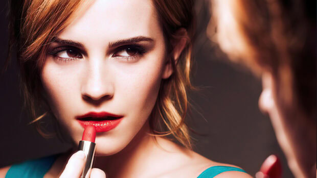 Woman applying red lipstick with focused look and natural skin texture