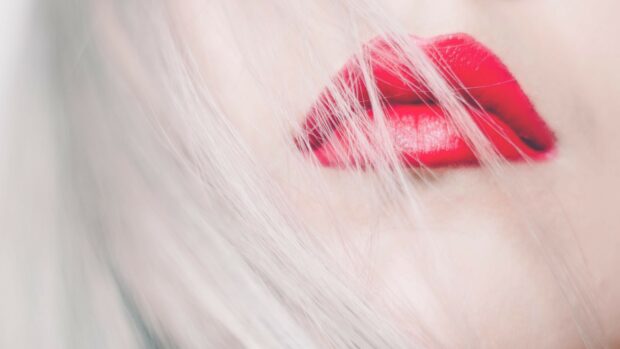 Close up of lips with bright red lipstick and white hair strands visible