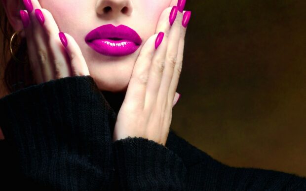 Close up of woman wearing vibrant lipstick and matching nail polish