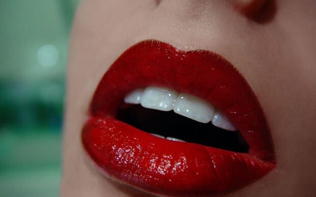 Close up of lips with red lipstick showing teeth