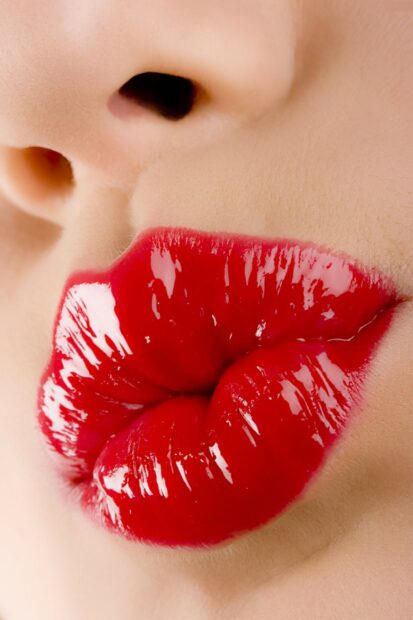 Close up of lips with vibrant red lipstick applied in high gloss texture