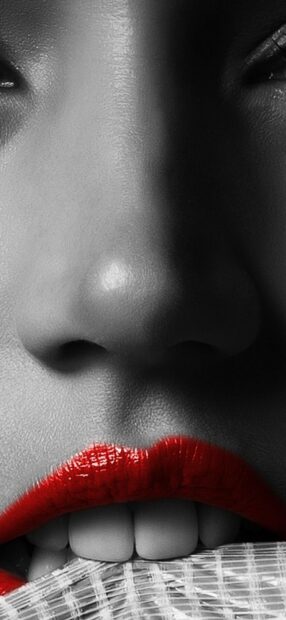 Close up of lips with vivid lipstick biting a textured cloth