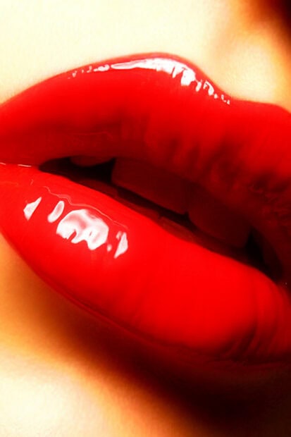 Close up of red glossy lips with vibrant lipstick on smooth skin