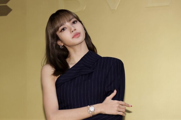 Lisa Blackpink wearing a stylish black pinstripe one shoulder outfit with a gold watch and accessories