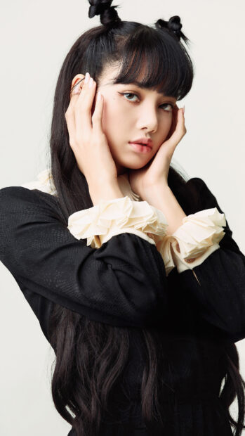 Young woman with long black hair posing with hands near face wearing black and white lace outfit Lisa Blackpink