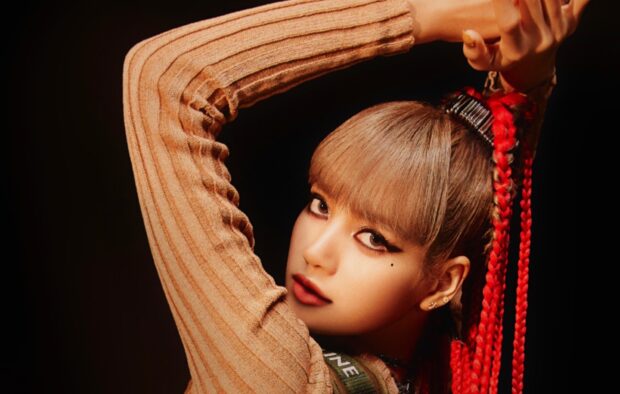Lisa Blackpink with braided red hair and stylish makeup posing with her arm raised