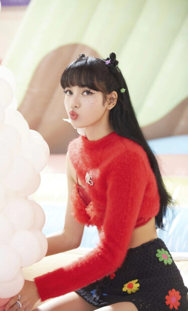 Lisa wearing a red sweater and black floral skirt with space buns hairstyle