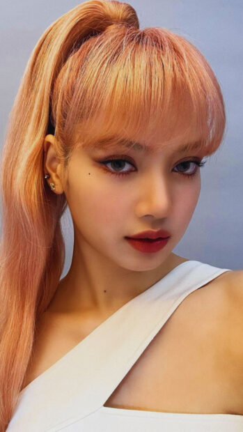 Close up of Lisa Blackpink with pink hair and white top looking at the camera